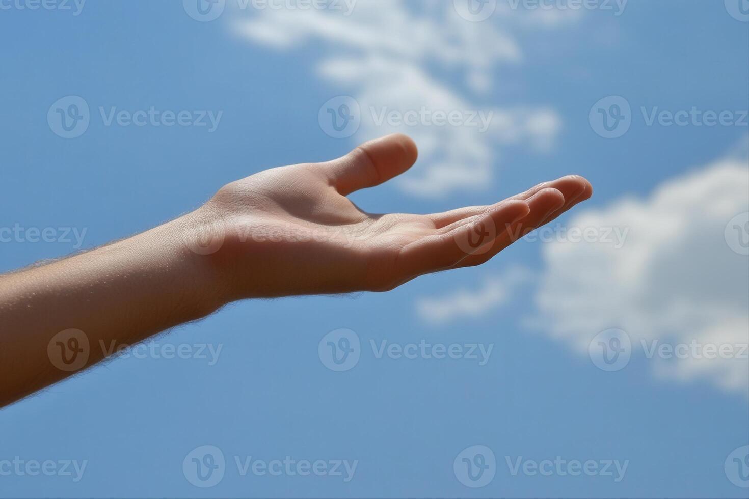 Outstretched hand reaching towards a bright blue sky with fluffy white clouds overhead photo