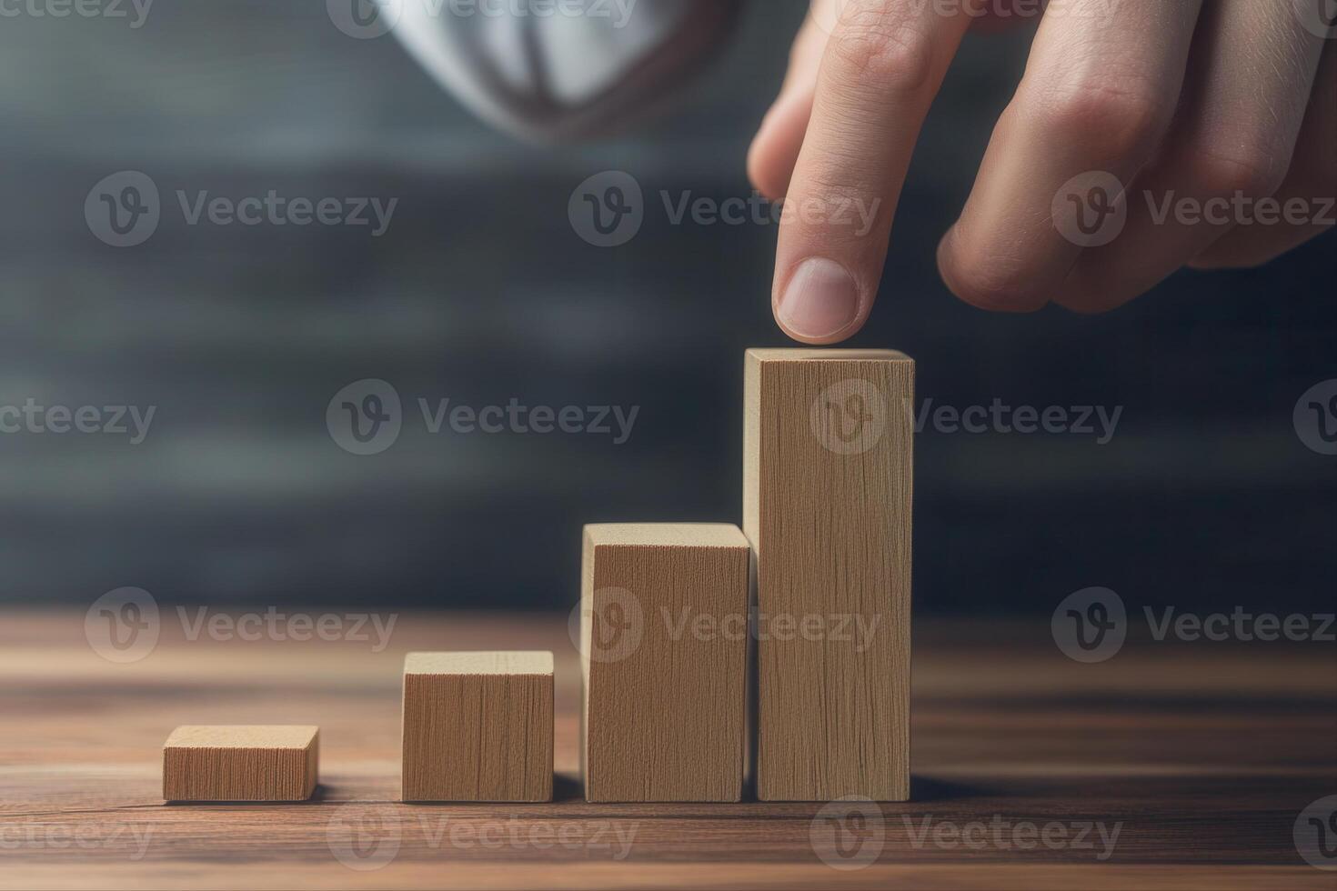 Hand arranging wooden blocks in a growing bar graph on a wooden table, symbolizing progress photo