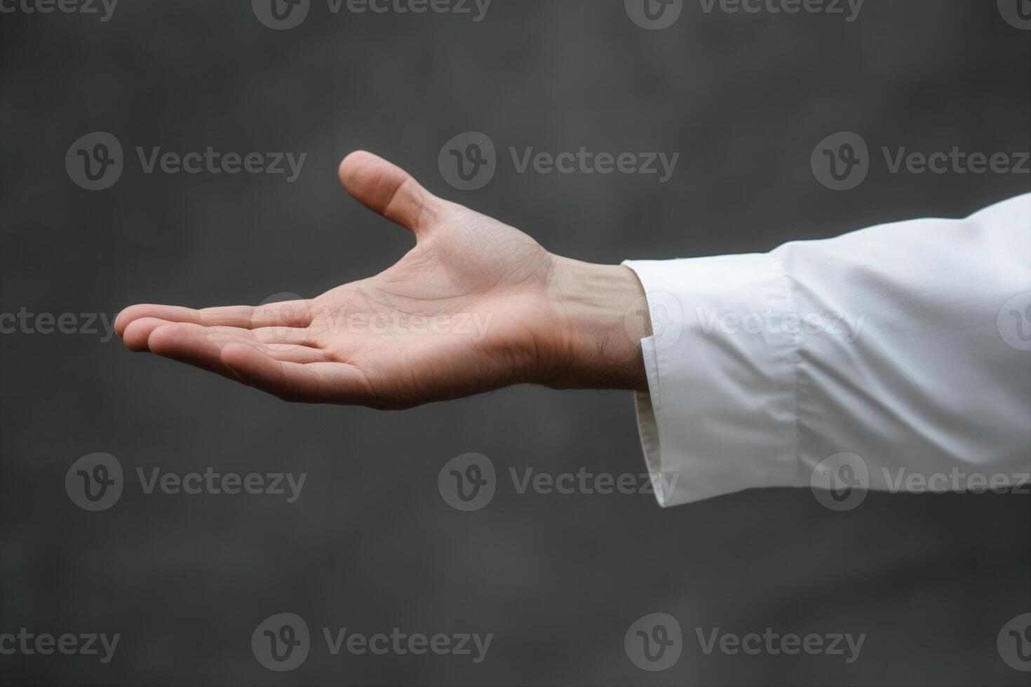 Outstretched hand in a white shirt against a blurred gray background, inviting gesture photo