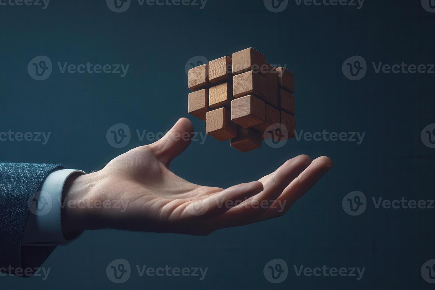 Hand holding a levitating wooden puzzle cube against a dark background, symbolizing creativity photo