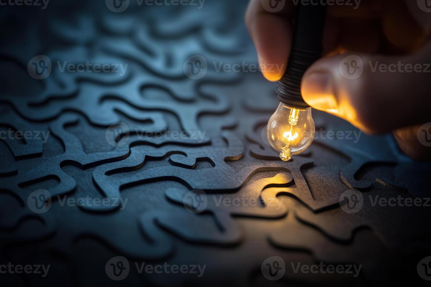 Hand holding a glowing light bulb over an intricate dark puzzle-like background photo