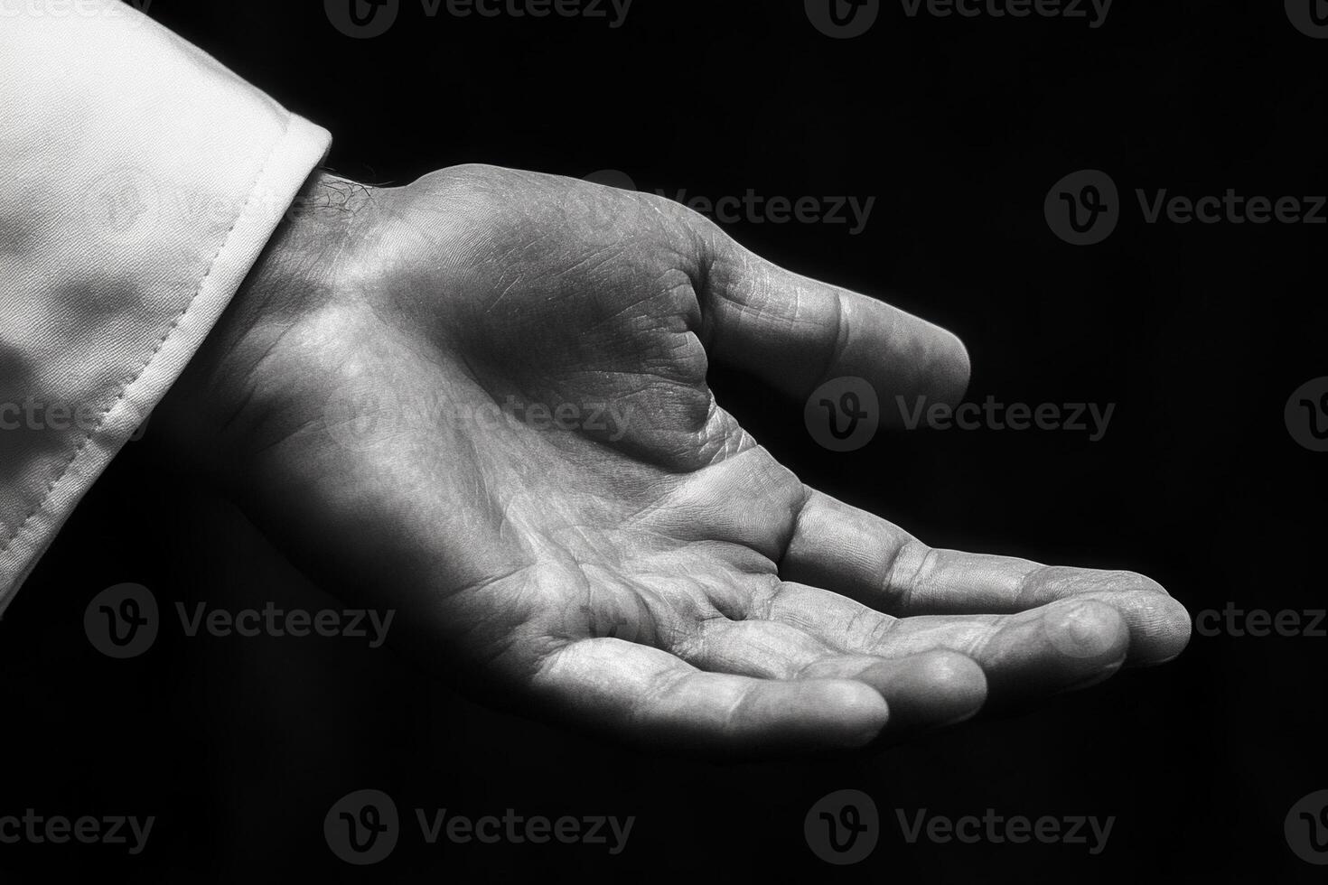 Outstretched hand in black and white, symbolizing generosity and support against a dark backdrop photo