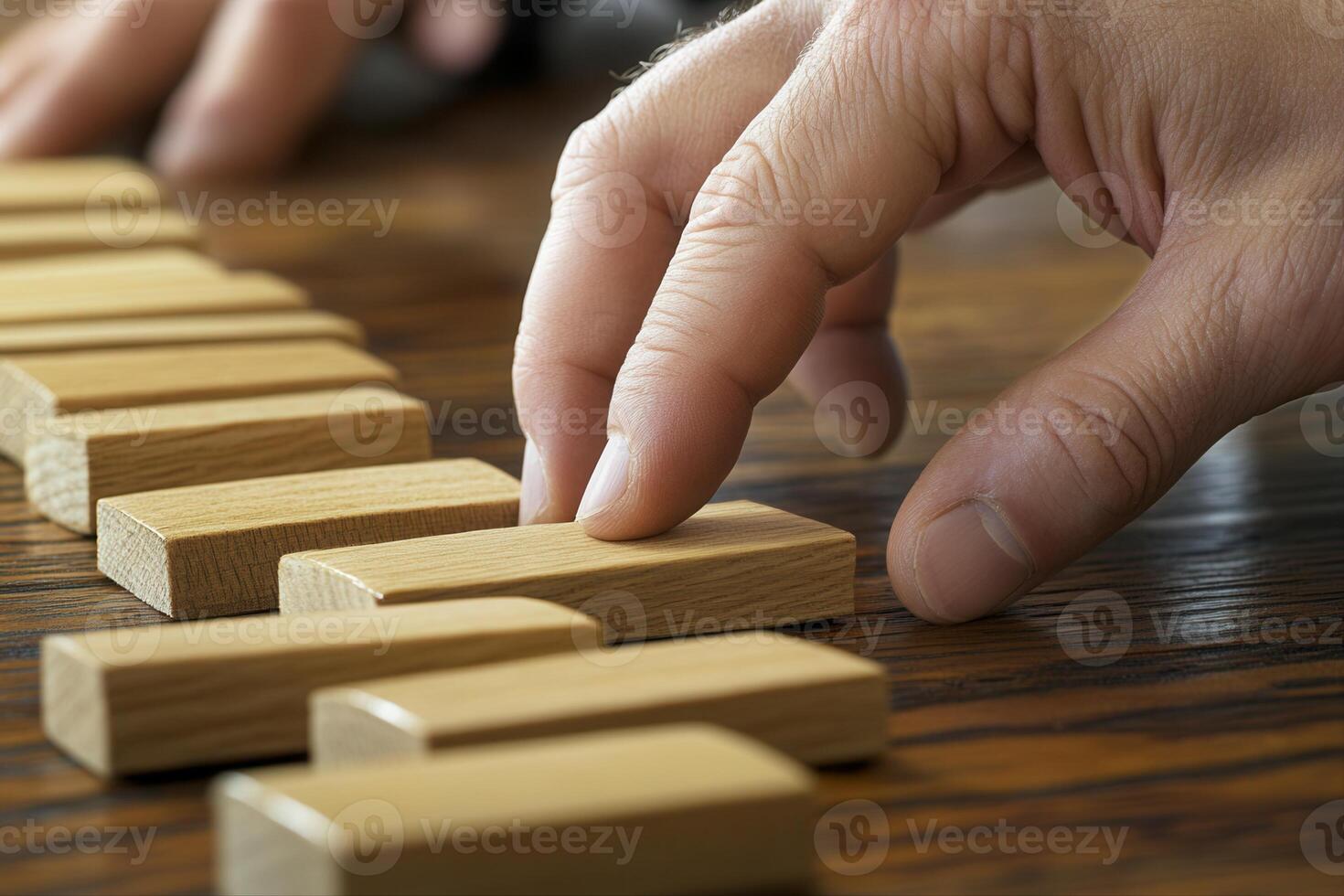 Hand arranging wooden blocks in a strategic manner on a wooden table, showcasing focus photo