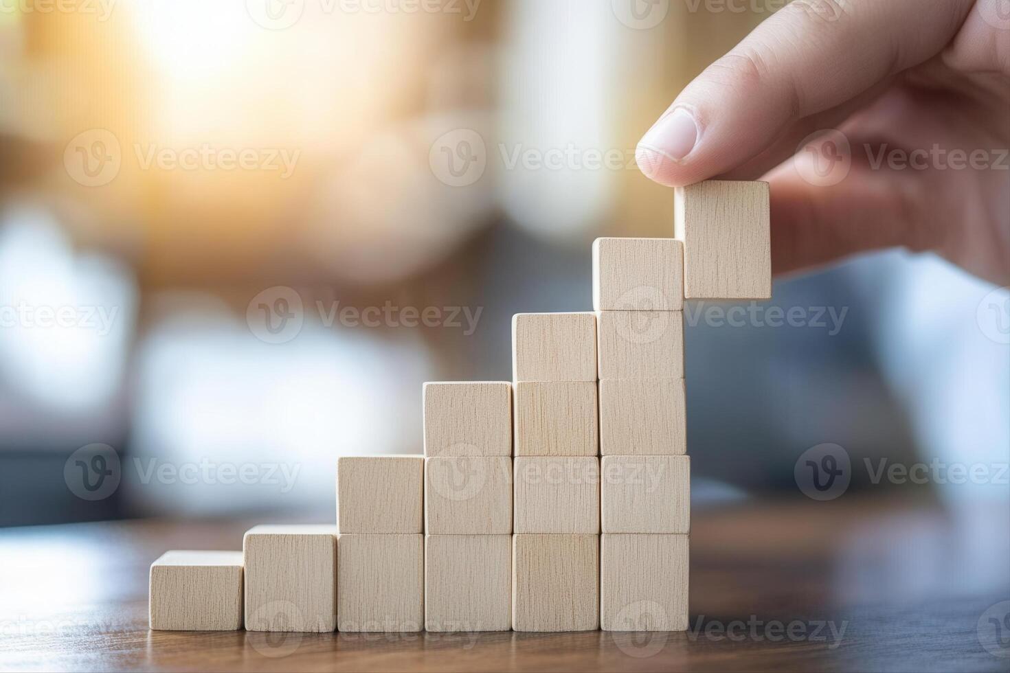 Hand placing a wooden block on a growing stack, symbolizing progress and success photo