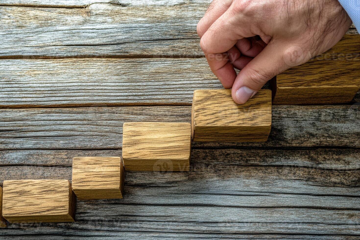Hand placing wooden blocks in a step formation on a rustic wooden surface, symbolizing progress photo