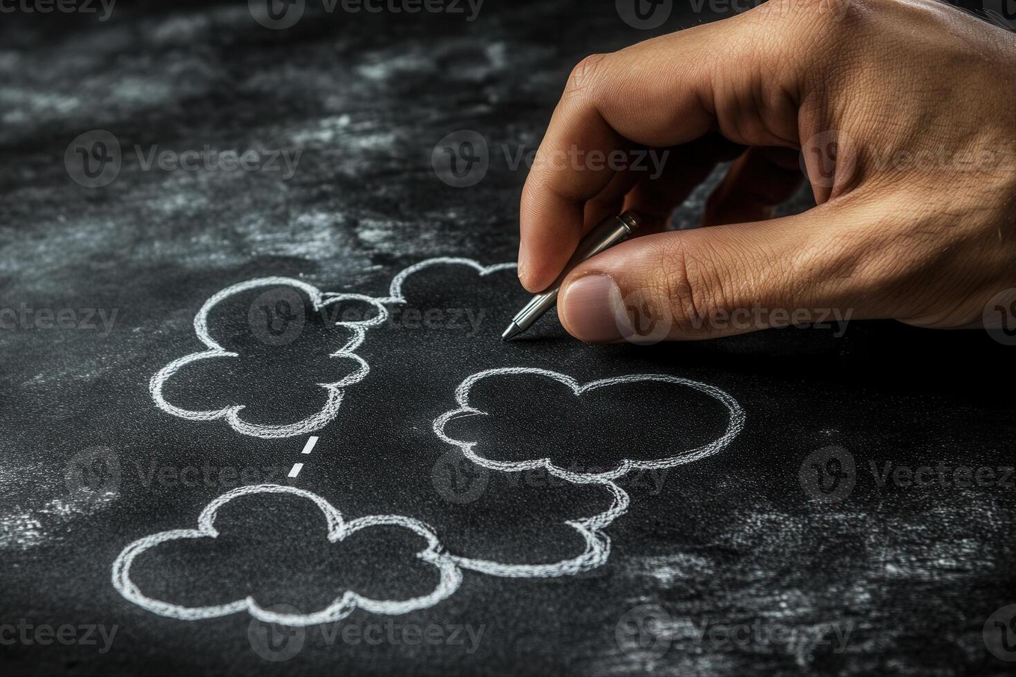 Hand drawing clouds on a chalkboard with a pen, creating a whimsical scene photo