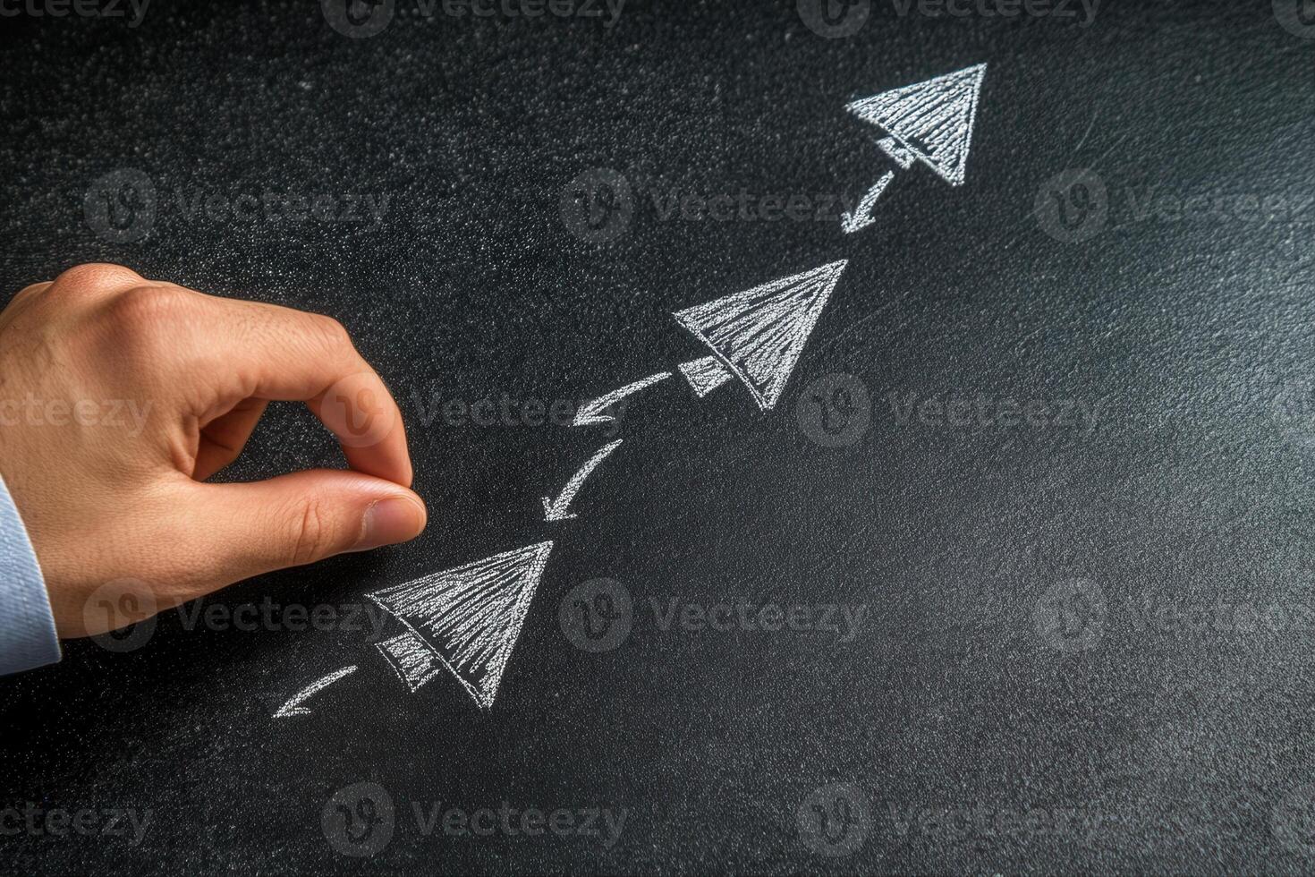 Hand drawing arrows on a chalkboard to symbolize growth and progress in business strategy photo
