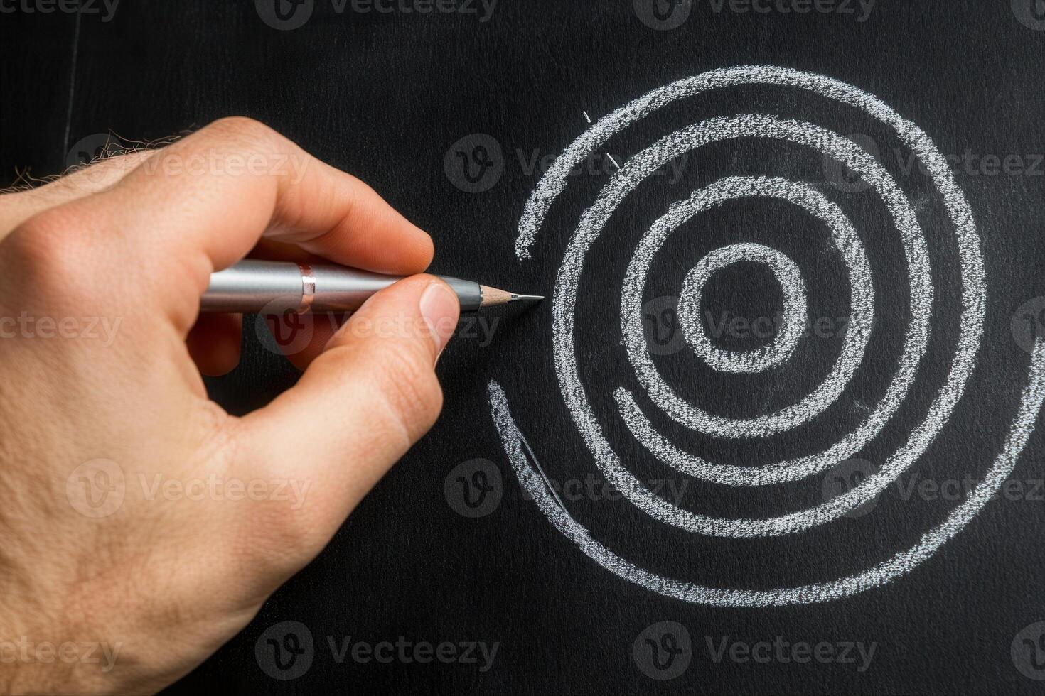 Hand drawing concentric circles on a blackboard with a pencil, showcasing creativity and focus photo
