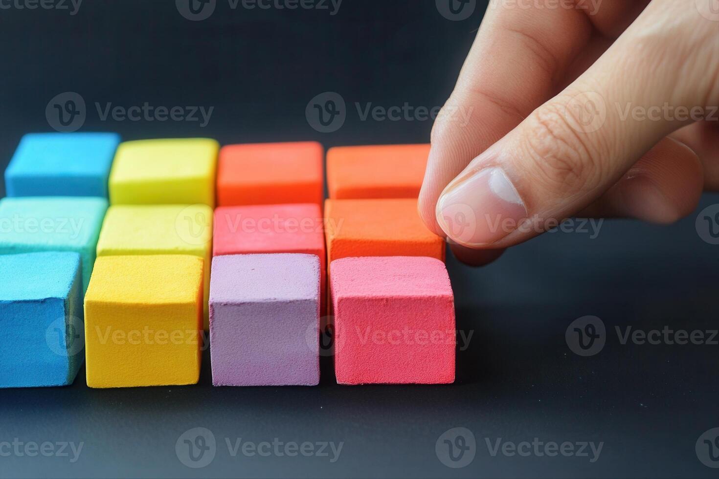 Hand arranging colorful wooden blocks in a creative pattern on a dark surface photo