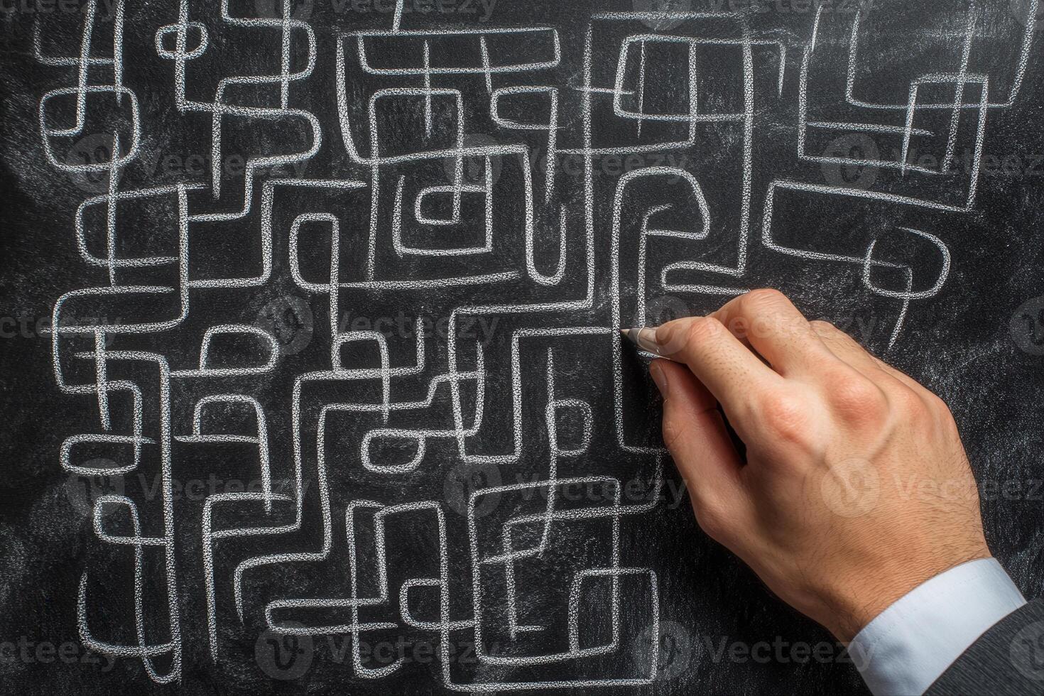Hand drawing intricate maze patterns on a blackboard with chalk in a creative workspace photo