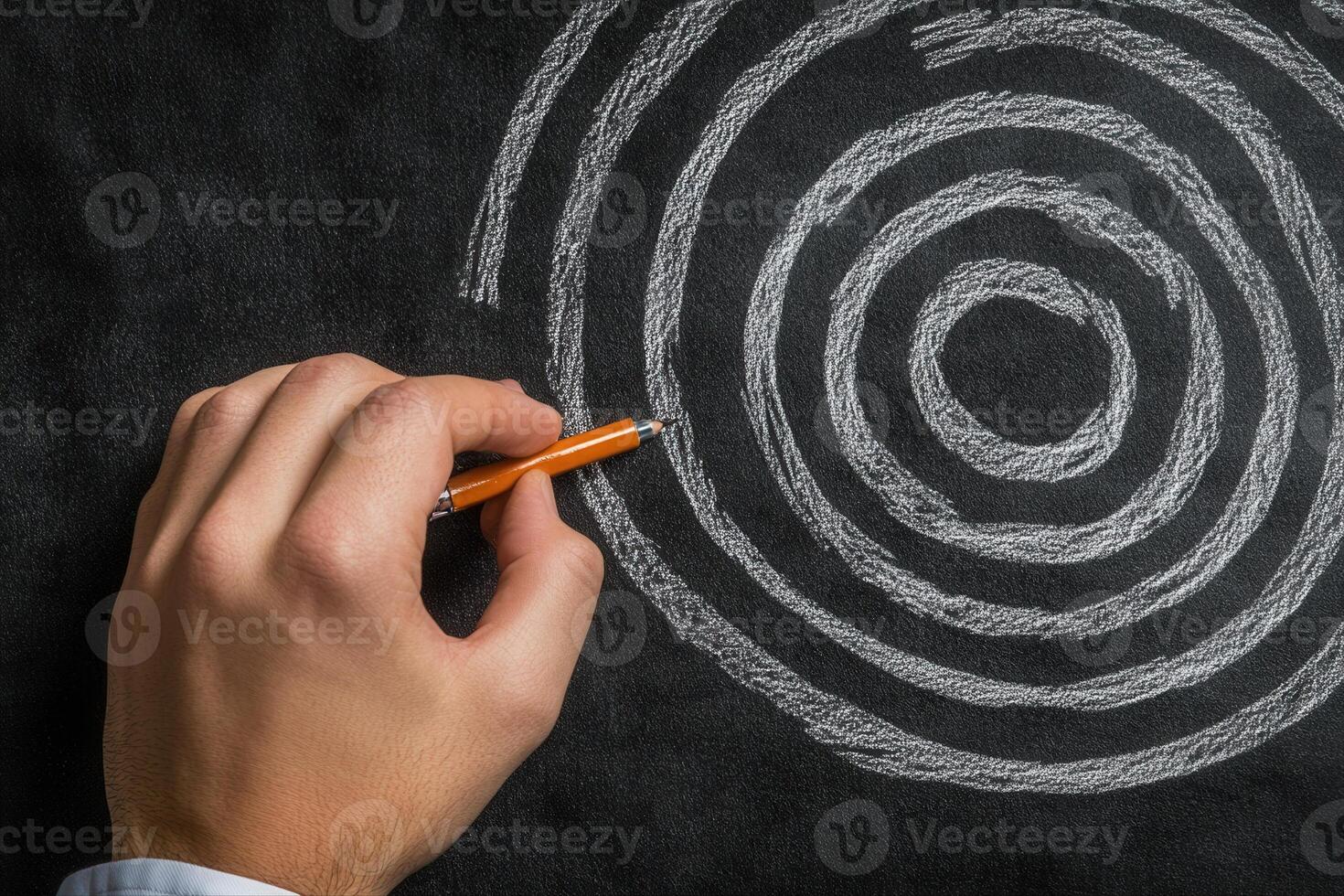 Hand drawing concentric circles on a blackboard with an orange pen, creative brainstorming session photo