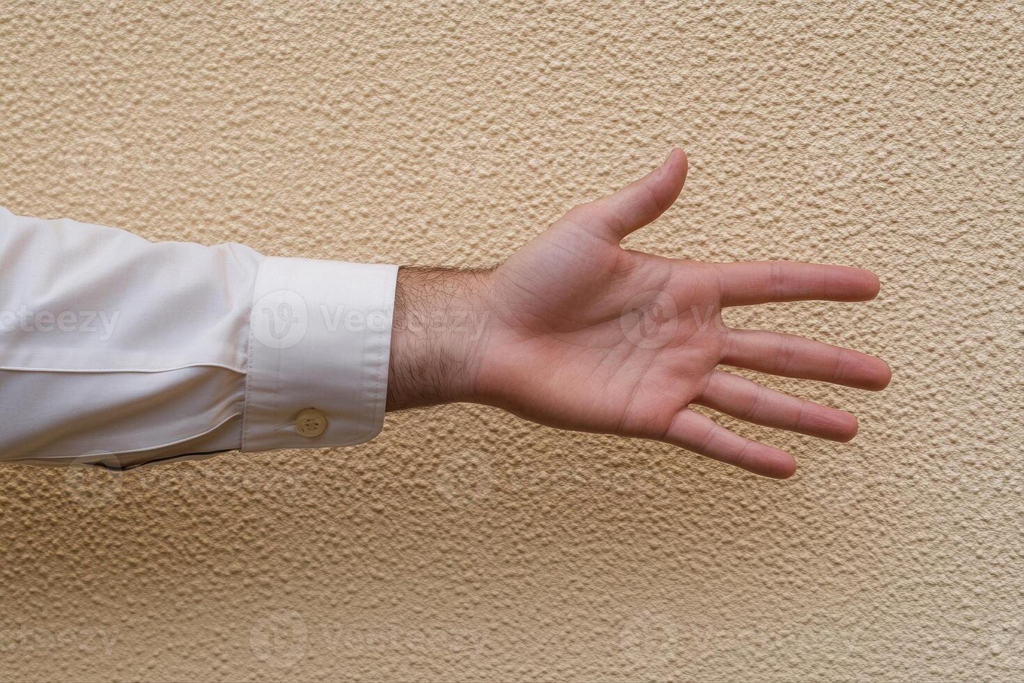 Outstretched hand against a textured wall, symbolizing invitation or greeting gesture photo