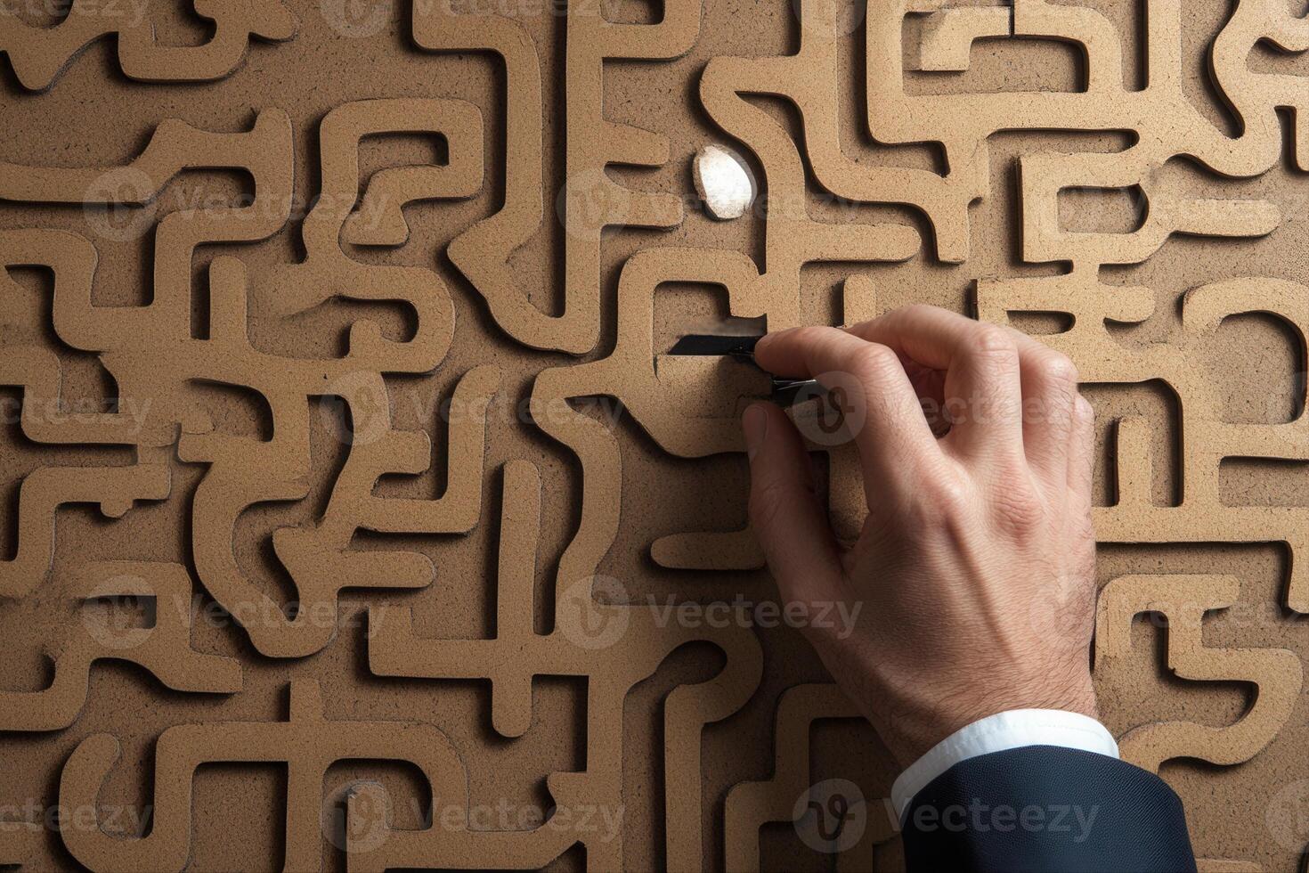 Hand navigating a complex maze on textured surface, symbolizing problem-solving and strategy photo