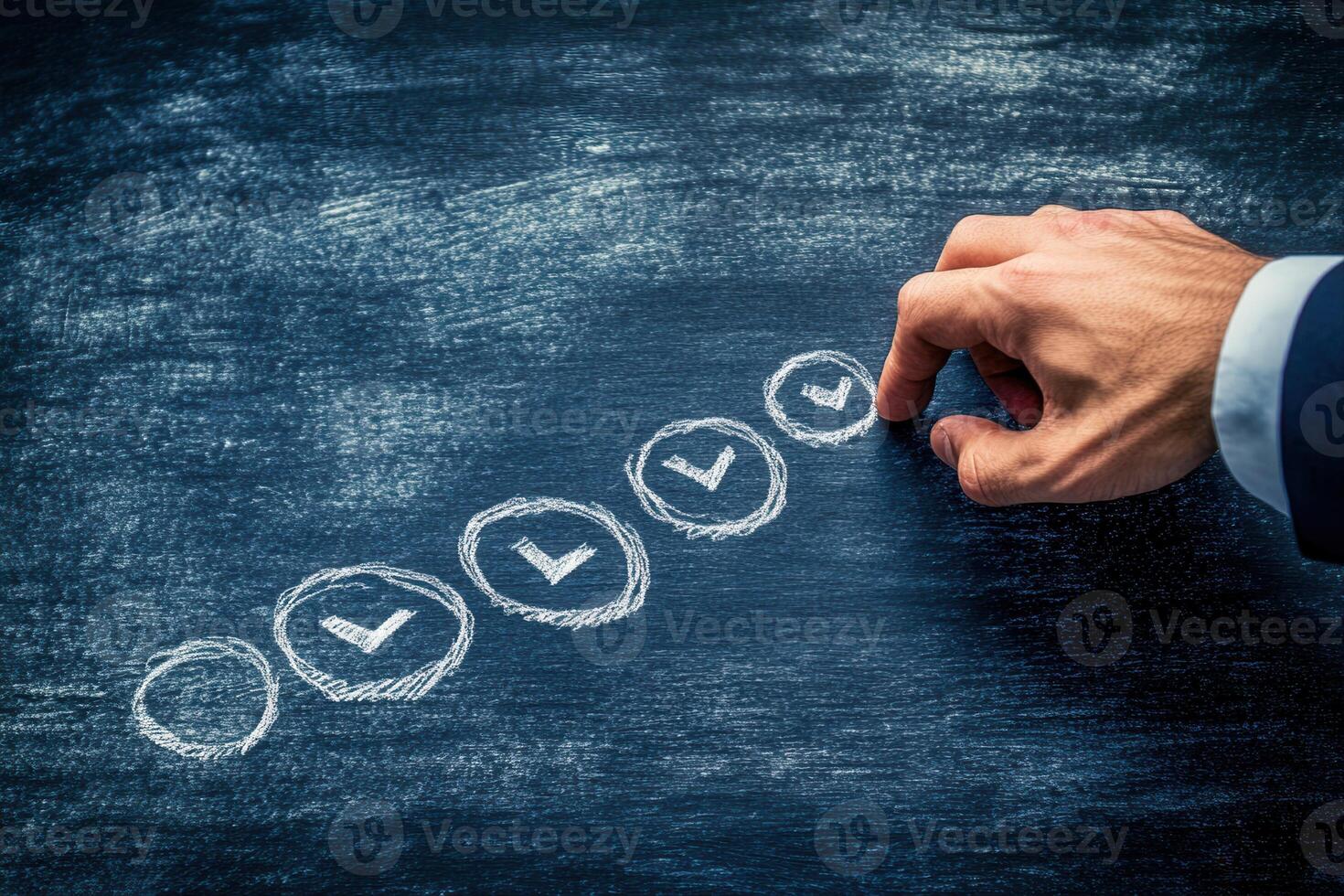 Hand marking checkboxes on a chalkboard, symbolizing progress in a business setting photo