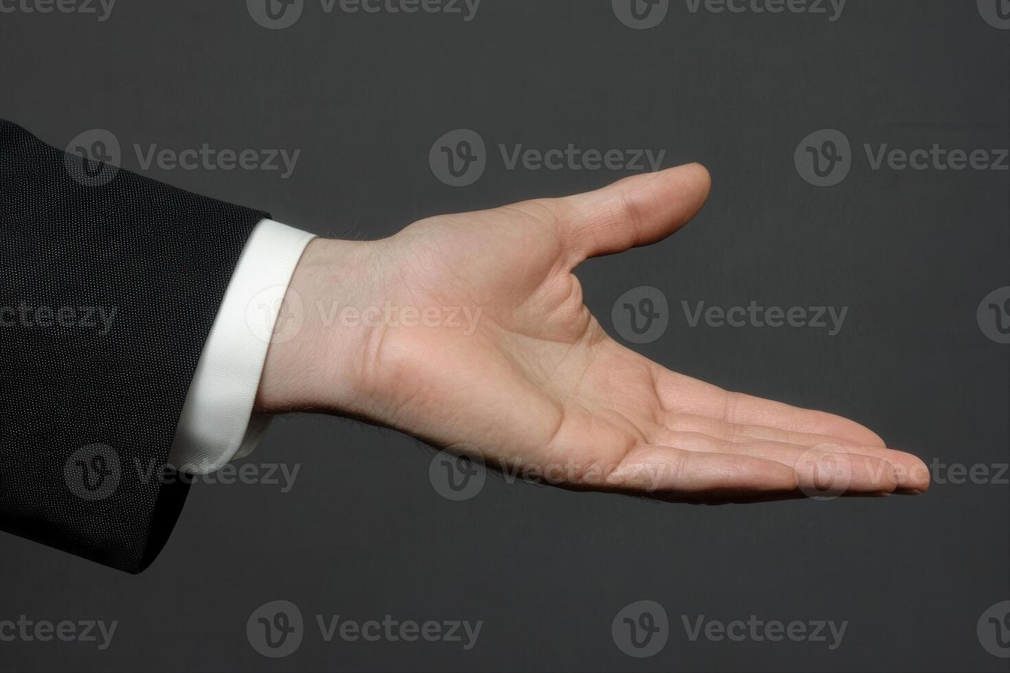 Outstretched hand in formal attire against a dark background, symbolizing invitation or agreement photo