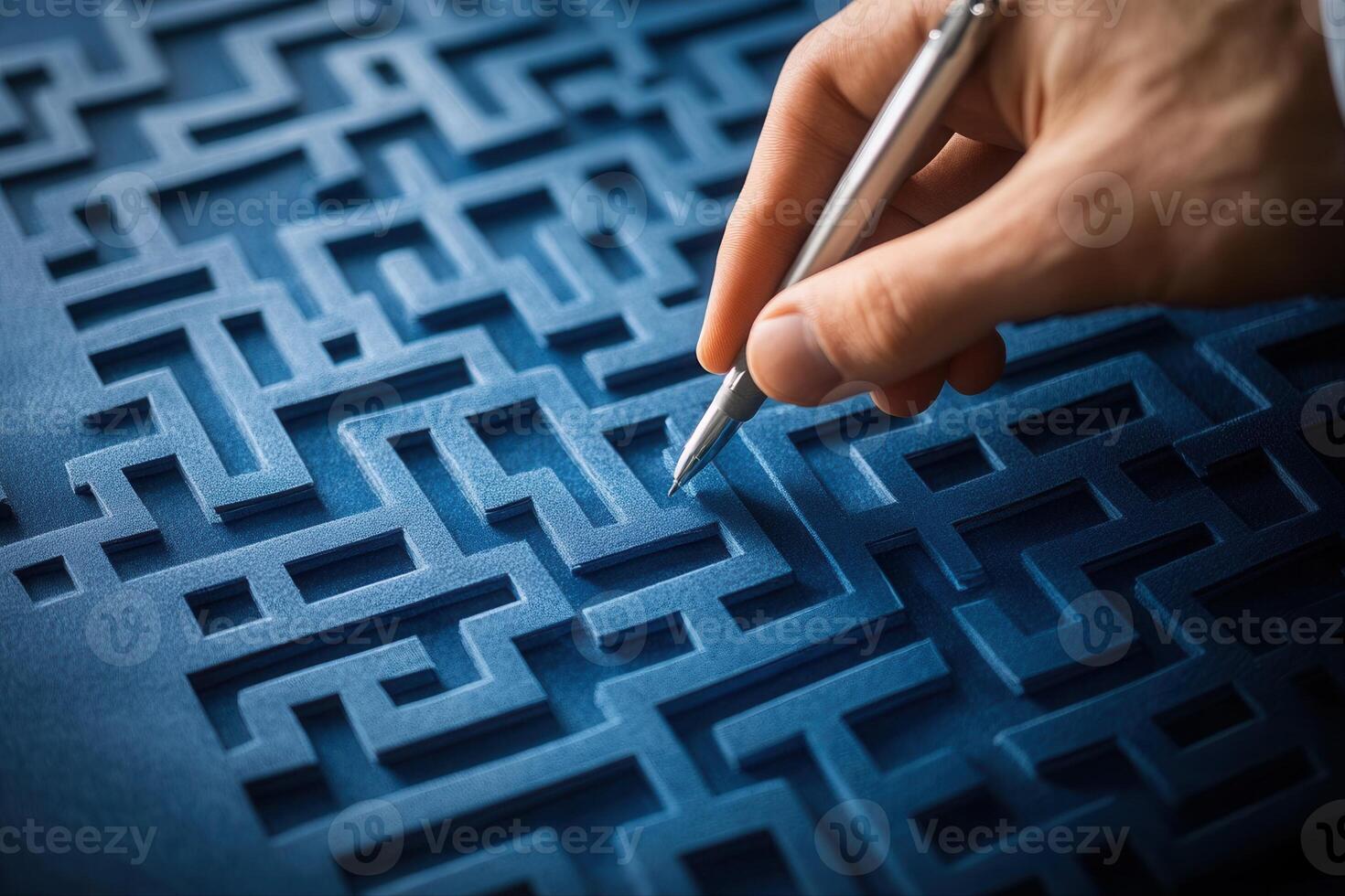 Hand holding a pen tracing intricate maze patterns on textured blue surface photo