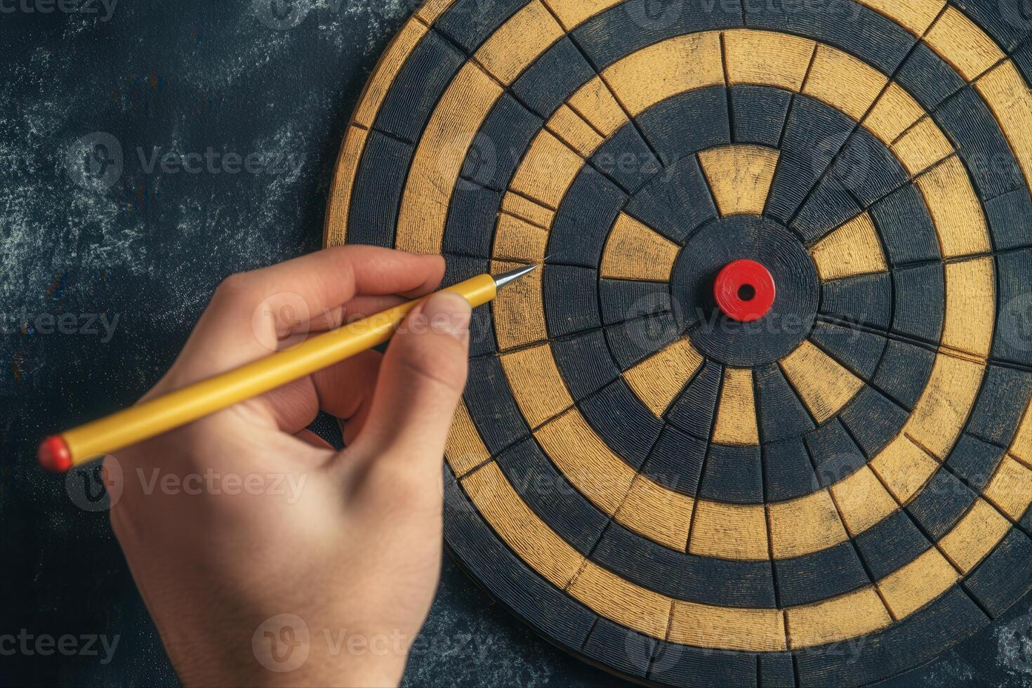 Hand holding a pencil poised to mark a target on a dartboard with a textured background photo