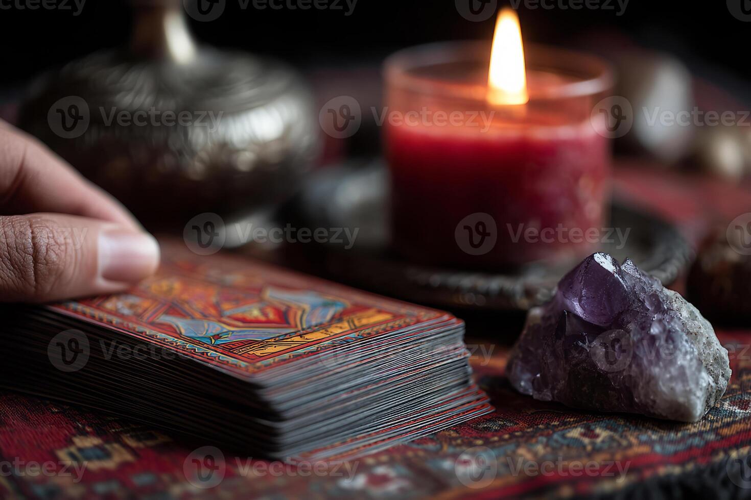 Hand touching tarot card deck near candle and amethyst photo