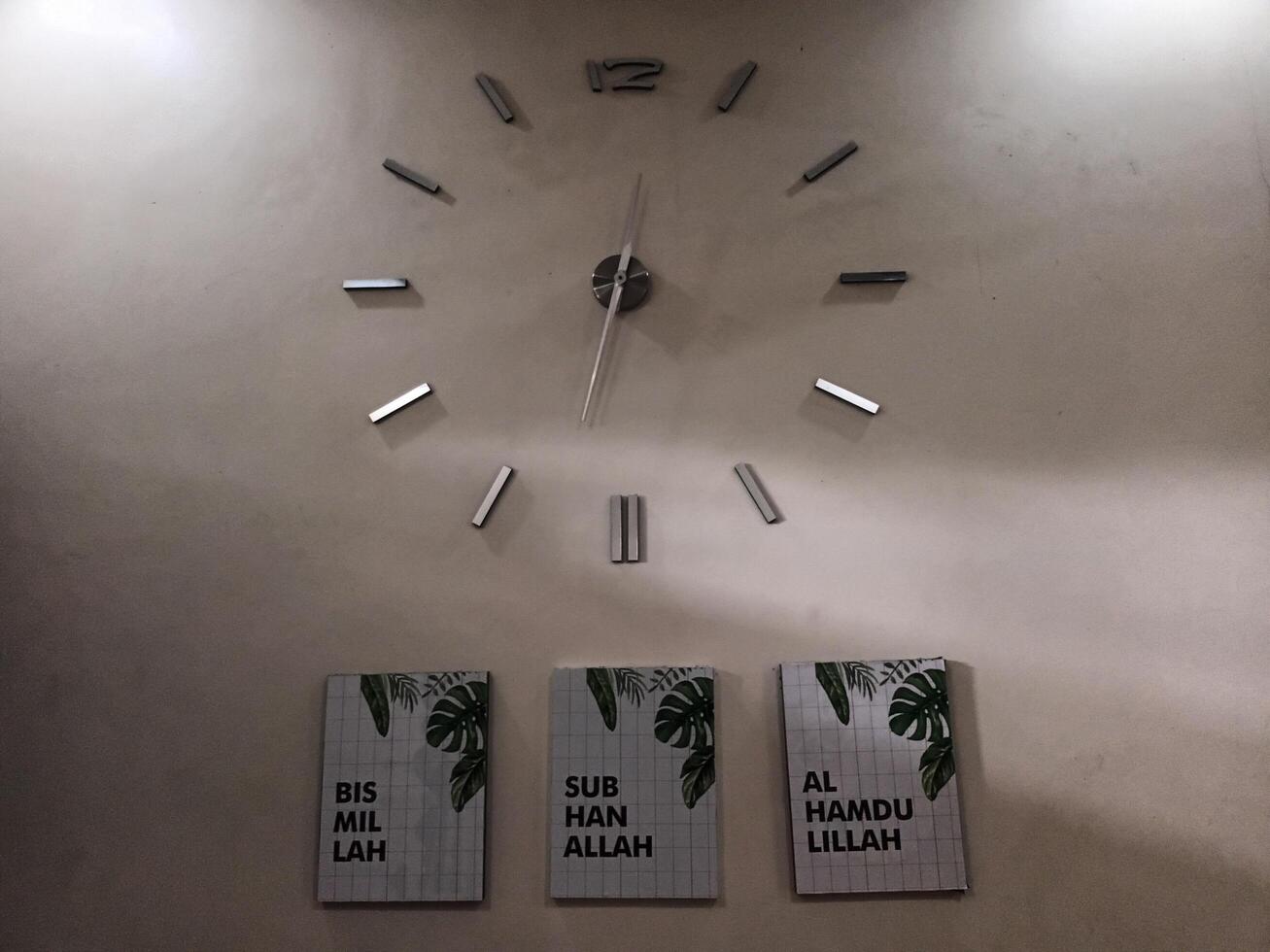 Modern Wall Clock Above Three Islamic Art Canvases. photo