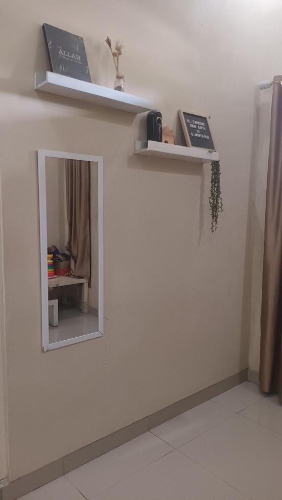 A Rectangular Wall Mirror Reflecting a Room with Shelves and Decorations. photo