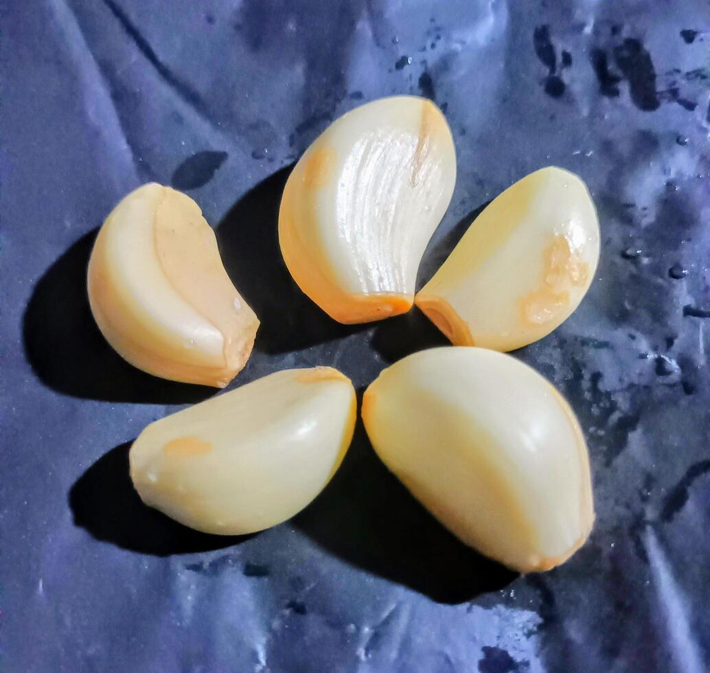Five Peeled Garlic Cloves on a Dark Surface photo