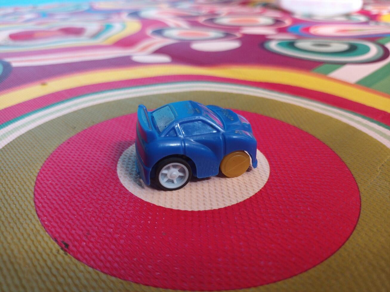 A Small Blue Toy Car on a Colorful Circular Patterned Surface. photo