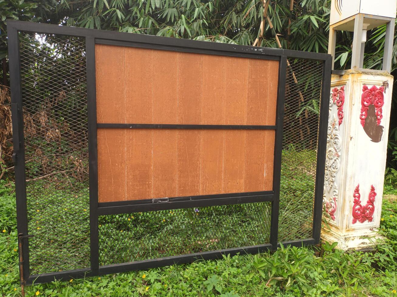 Empty Brown Signboard with Black Metal Frame in a Green Outdoor Setting. photo