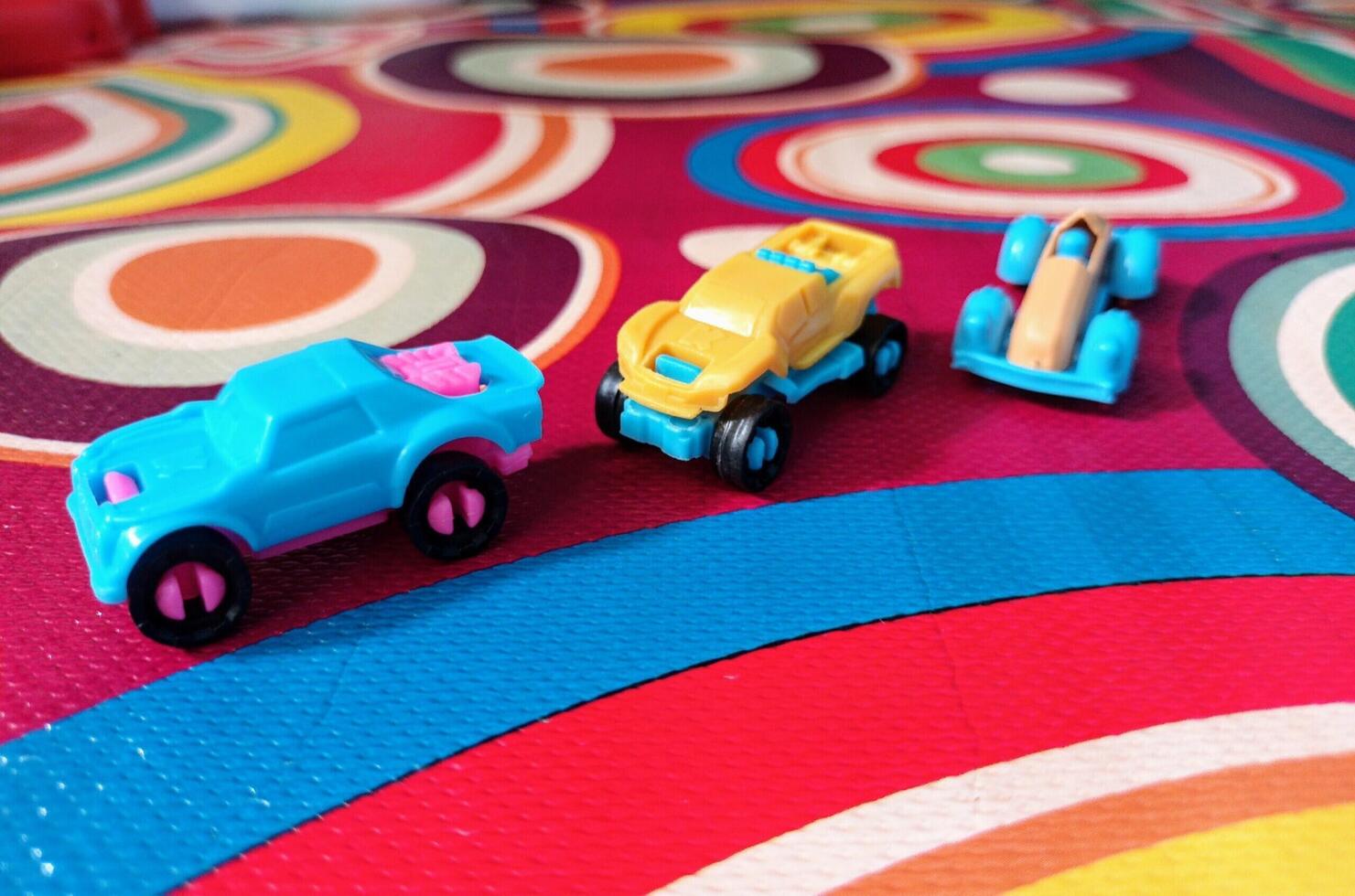 Three Small Toy Cars on a Colorful Circular Patterned Mat. photo