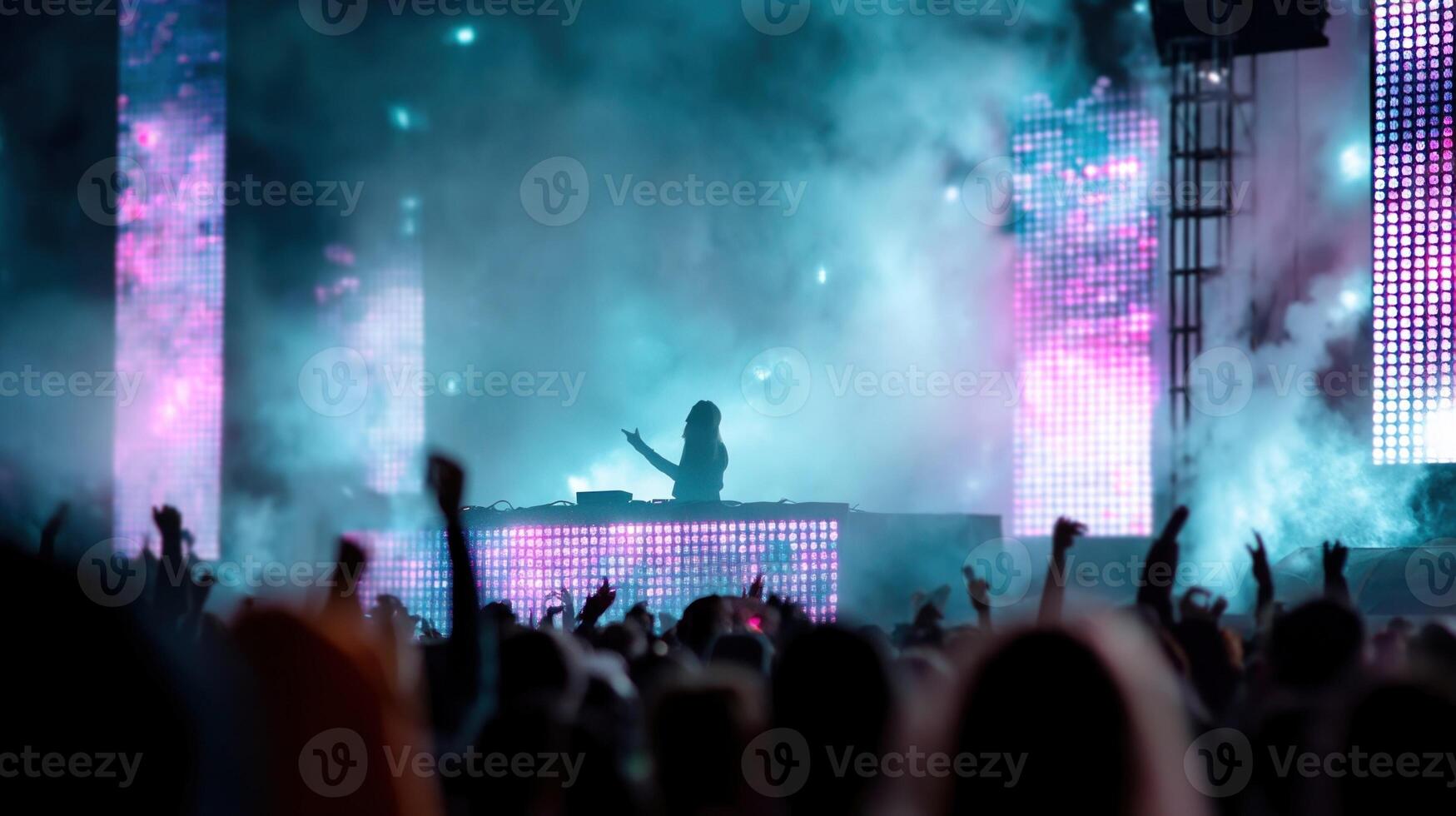 A DJ mixing tracks at a festival surrounded by pulsating LED screens and a crowd jumping in sync with the beat all illuminated by vibrant dynamic colors photo
