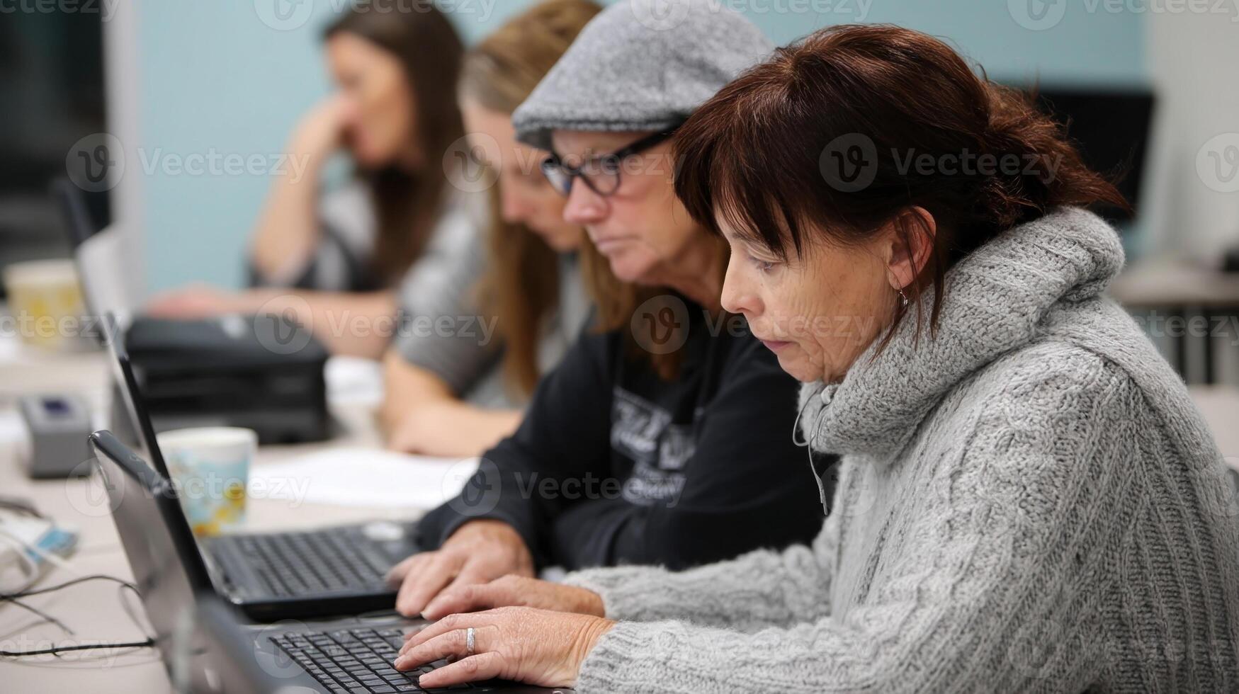 Mature women learning computer skills in classroom photo