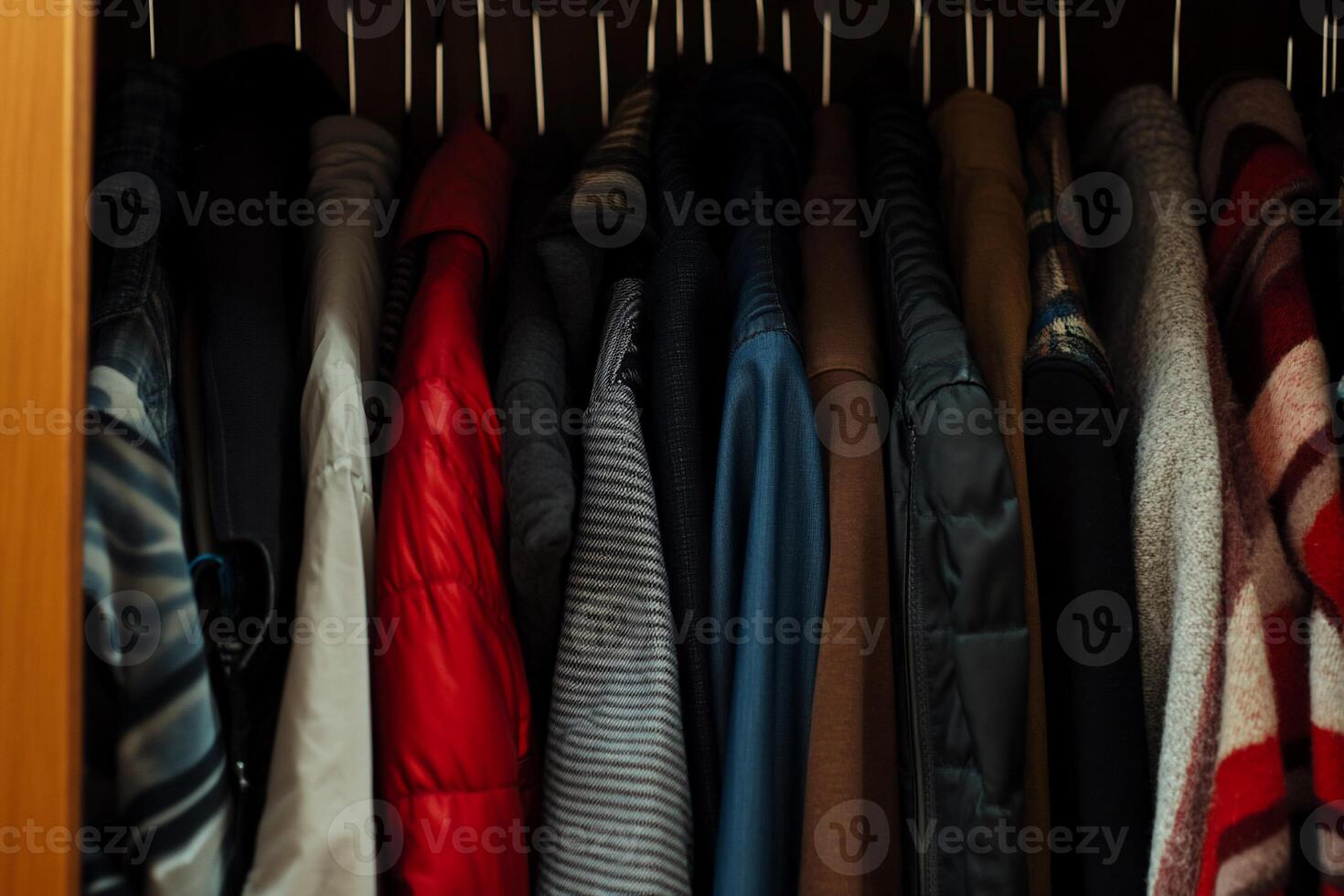 Clothes hanging neatly in a closet. Various colors and styles of jackets and shirts photo