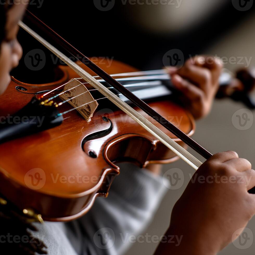 Close-up of child playing violin. Hands hold bow, fingers on strings. Wood instrument photo