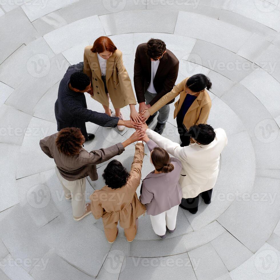 Diverse group stands in a circle, hands clasped together, unified photo