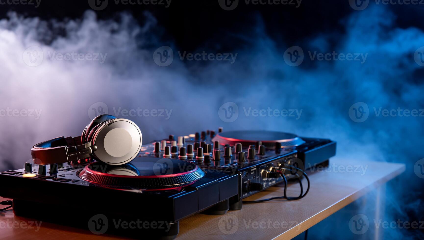 DJ equipment on a table, surrounded by smoke. A pair of headphones sits on top of a mixing console with turntables photo