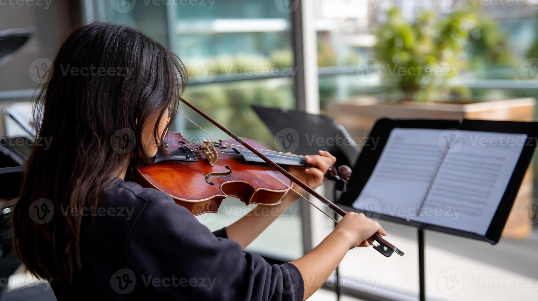 Young woman plays violin outdoors. Focused musician practicing photo