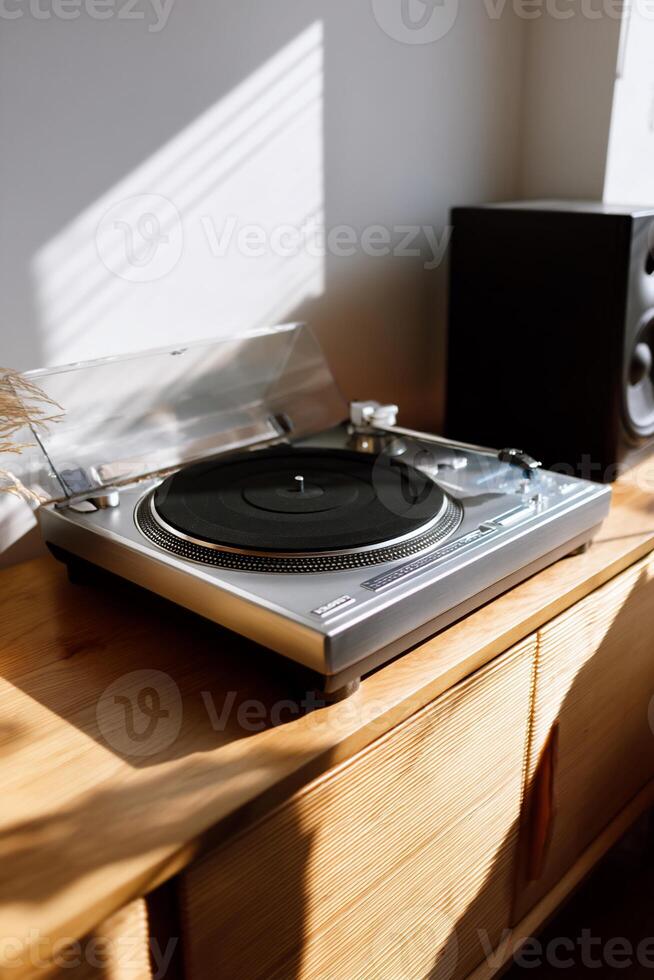 Record player on light wooden cabinet, sunlight streams in photo