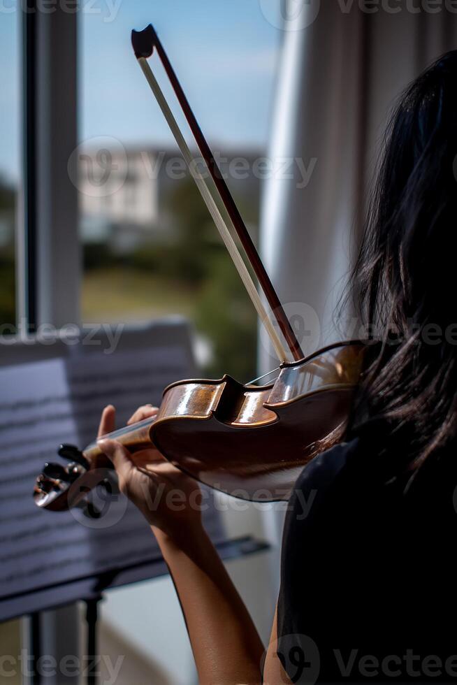 A person plays a violin near a window. Music lesson or practice photo