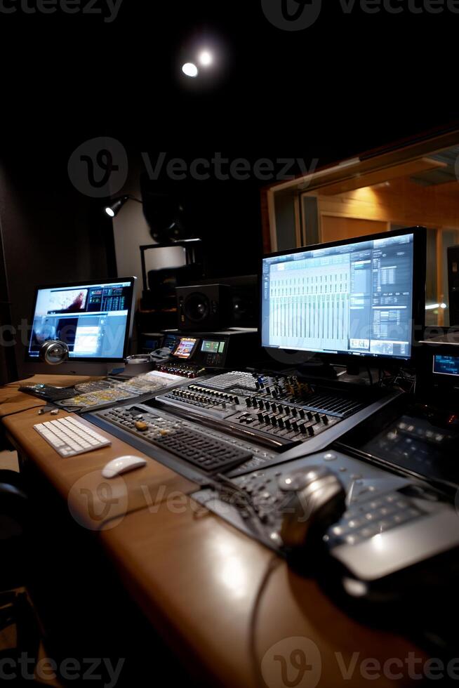 Professional audio recording studio interior. Multiple computer monitors, audio control panel, and equipment are visible photo