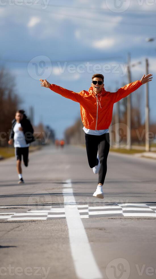 Runner in orange jacket crosses finish line, another runner behind photo