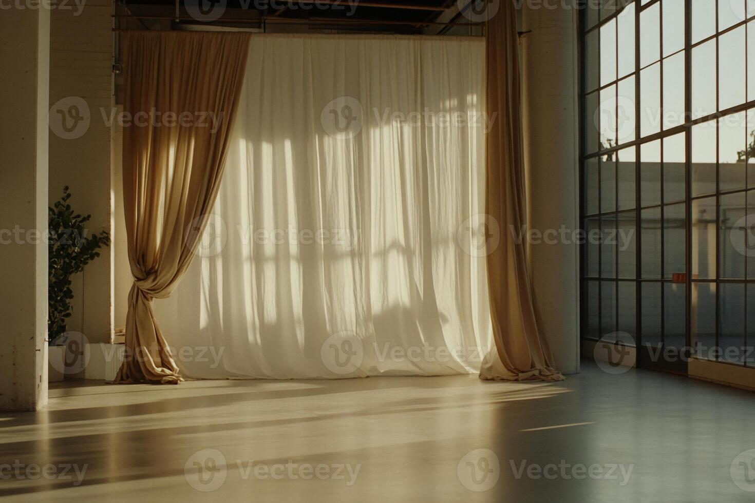 Empty studio space with sheer curtains, sunlight filtering through large windows photo