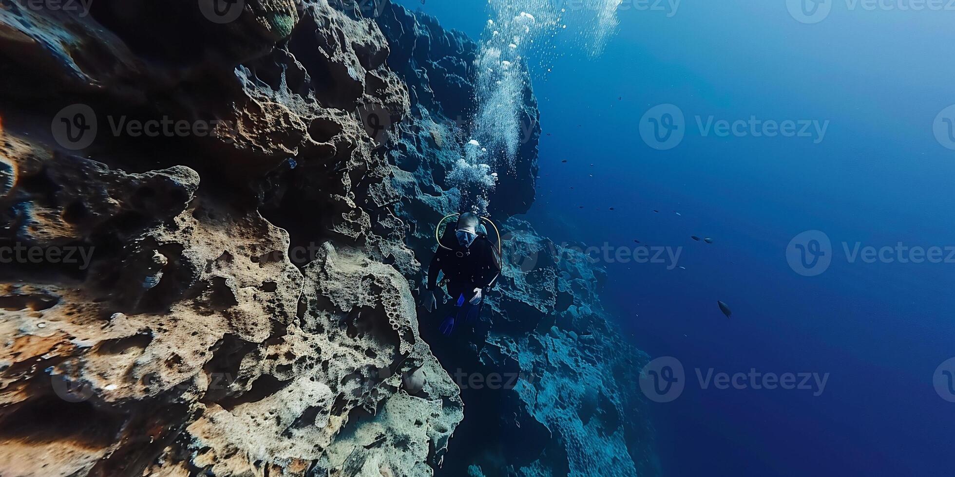 Underwater diver exploring a rocky cliff face photo