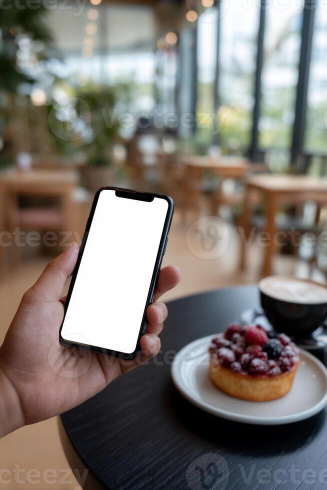 Smartphone held in hand, cafe setting, empty screen, pastry and coffee photo