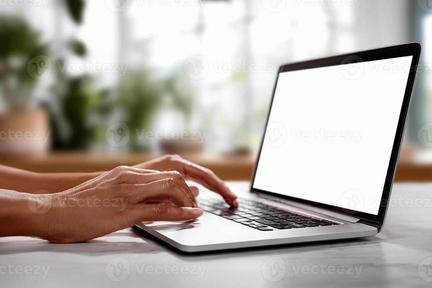 Hands typing on a laptop with a blank screen, in a bright, home office setting photo