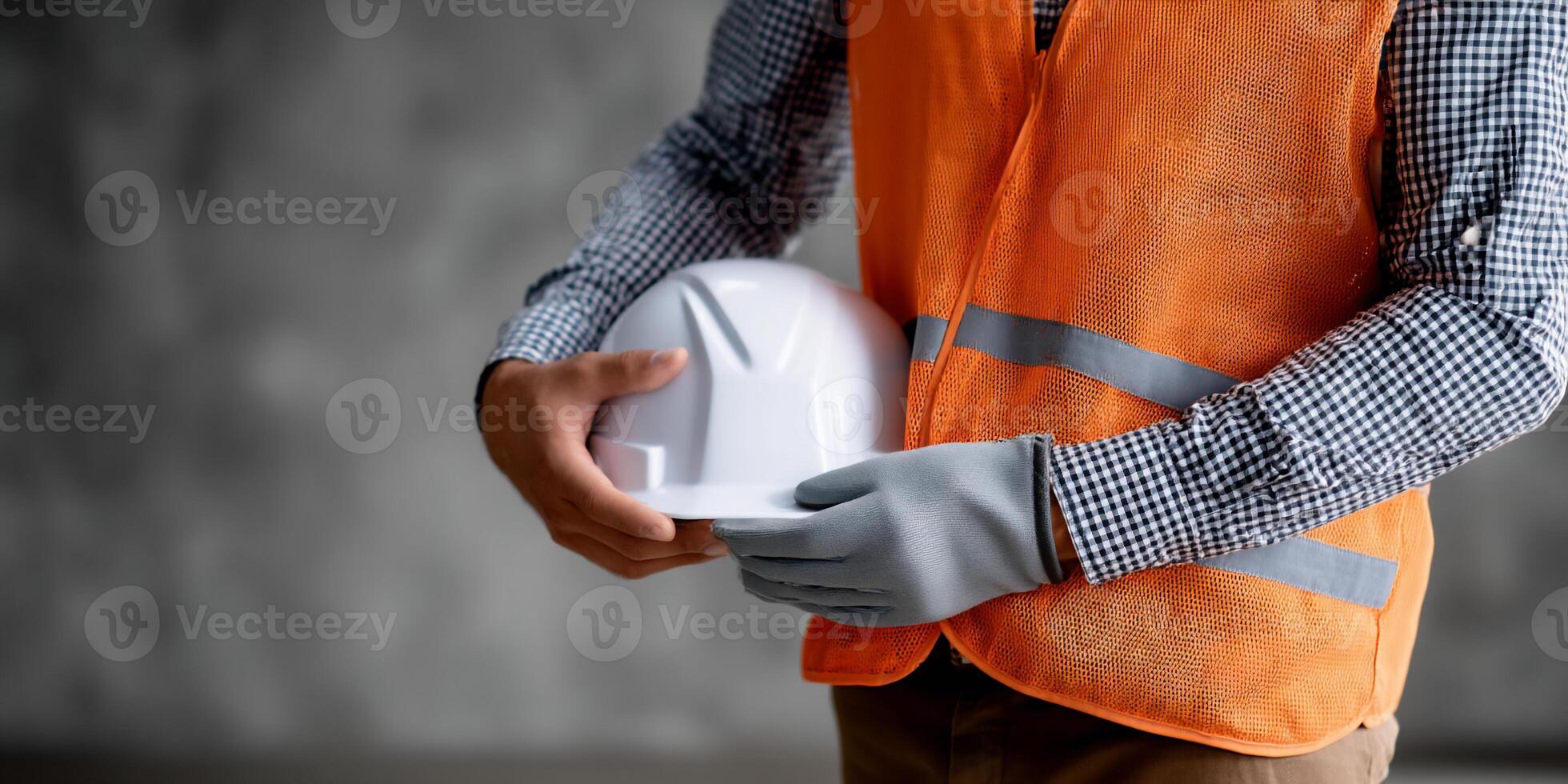 A man in an orange vest and safety vest holding a white hard hat photo