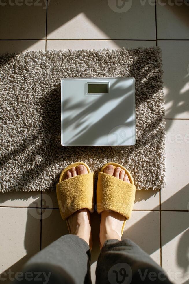 Person's feet in yellow slippers, digital scale on a rug photo