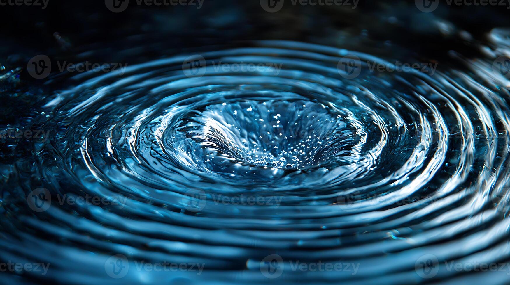 A circular water droplet is seen in the middle of a blue background photo
