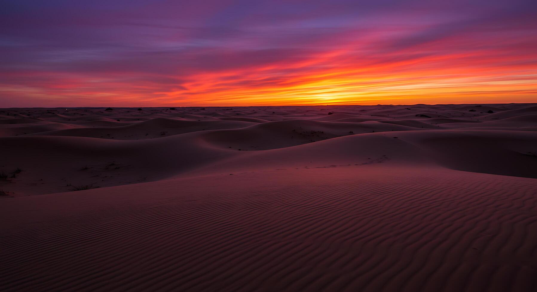 A desert with sand dunes and a colorful sunset photo