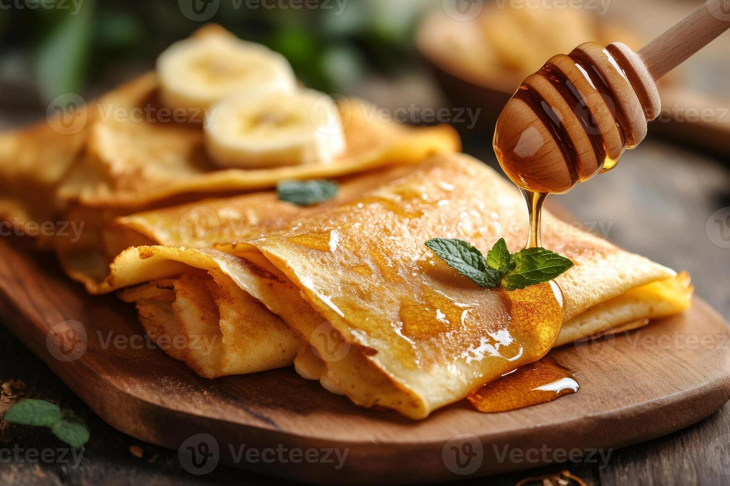 Delicious crepes with honey and banana slices being drizzled on wooden board photo