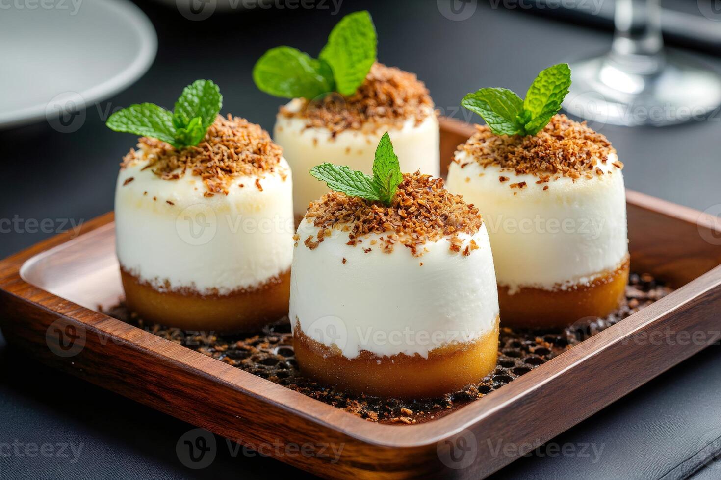 Delicious mini cakes with coconut flakes and fresh mint on wooden tray photo