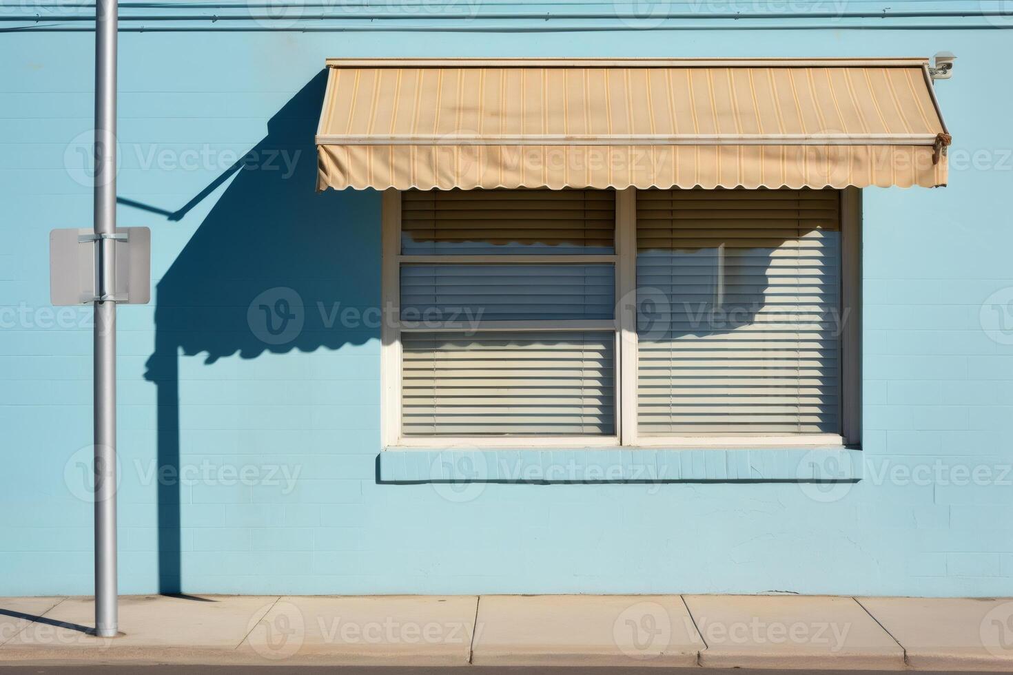 Sunlight casting shadows on light blue wall with window and awning photo